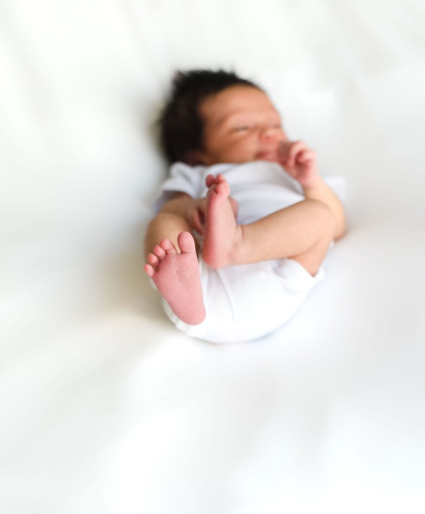 a newborn rests on a white blanket newborn photography safety