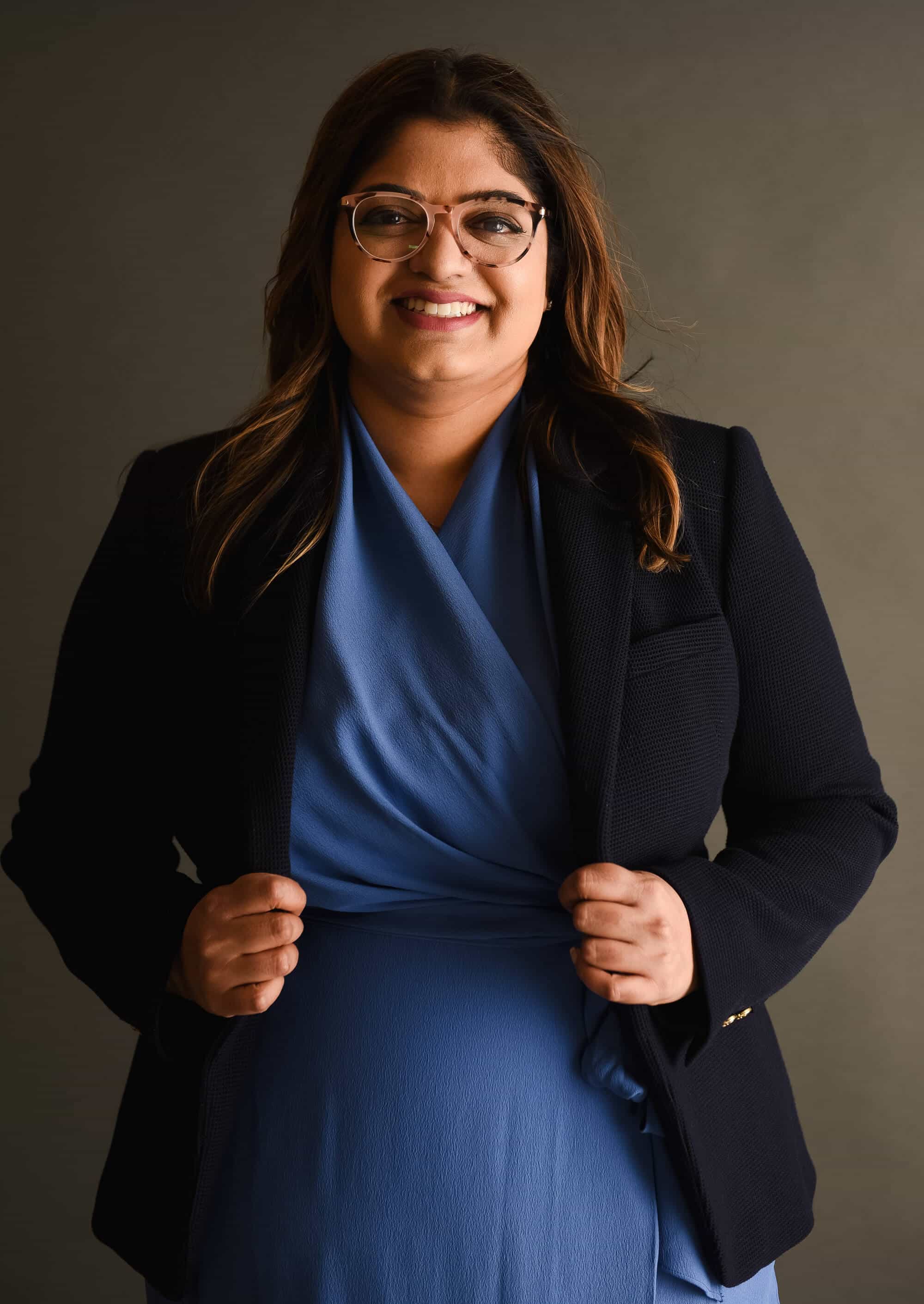 a profession woman poses wearing a blue dress and black blazer<br />
