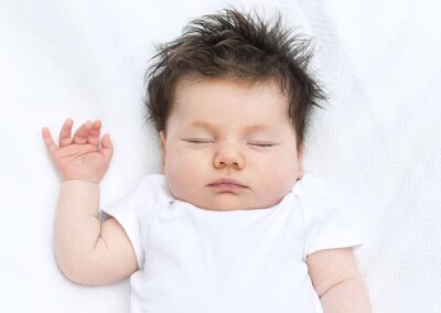 a newborn is asleep in a white blanket in Denver