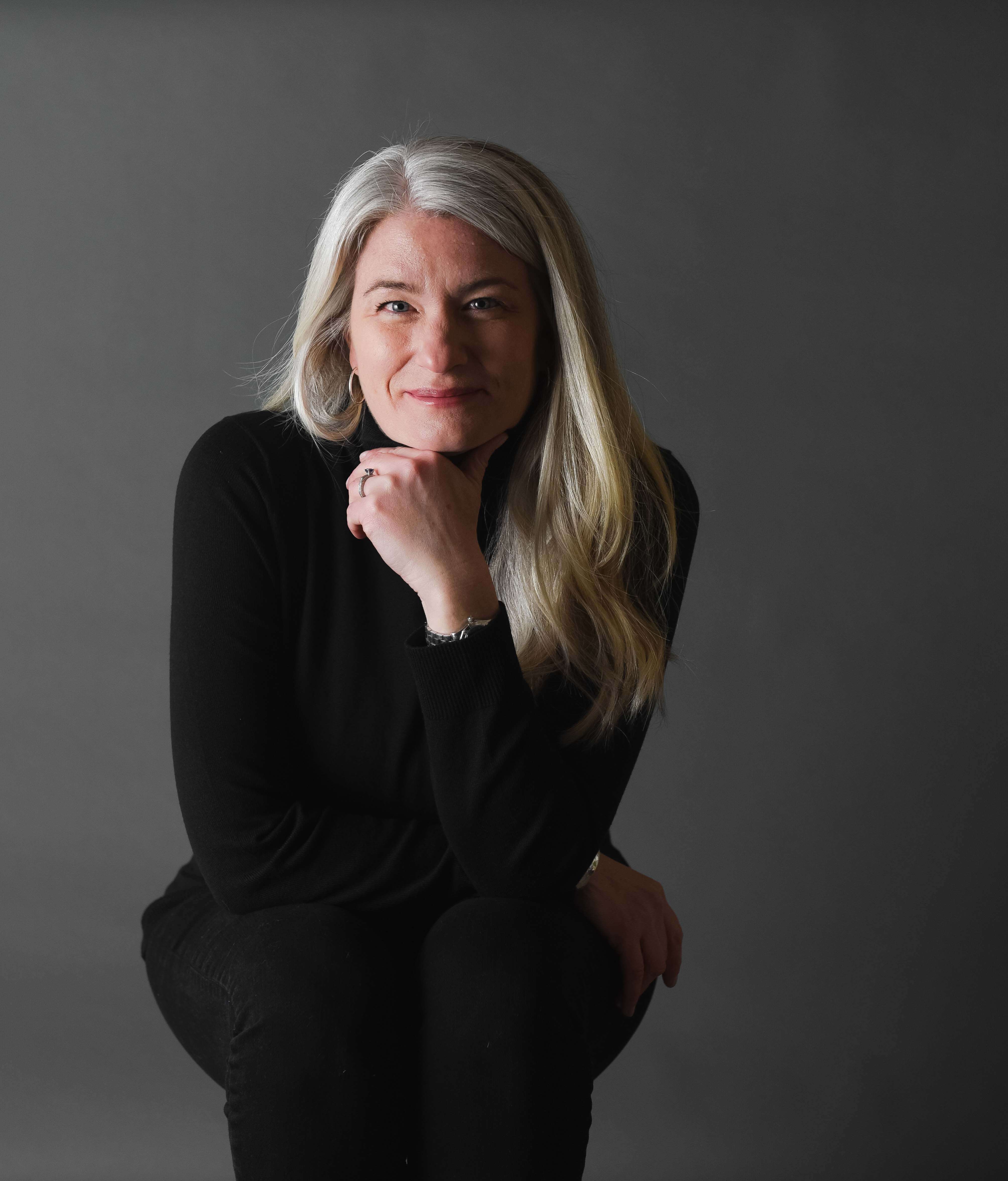 a women dressed in all black poses for a headshot in denver