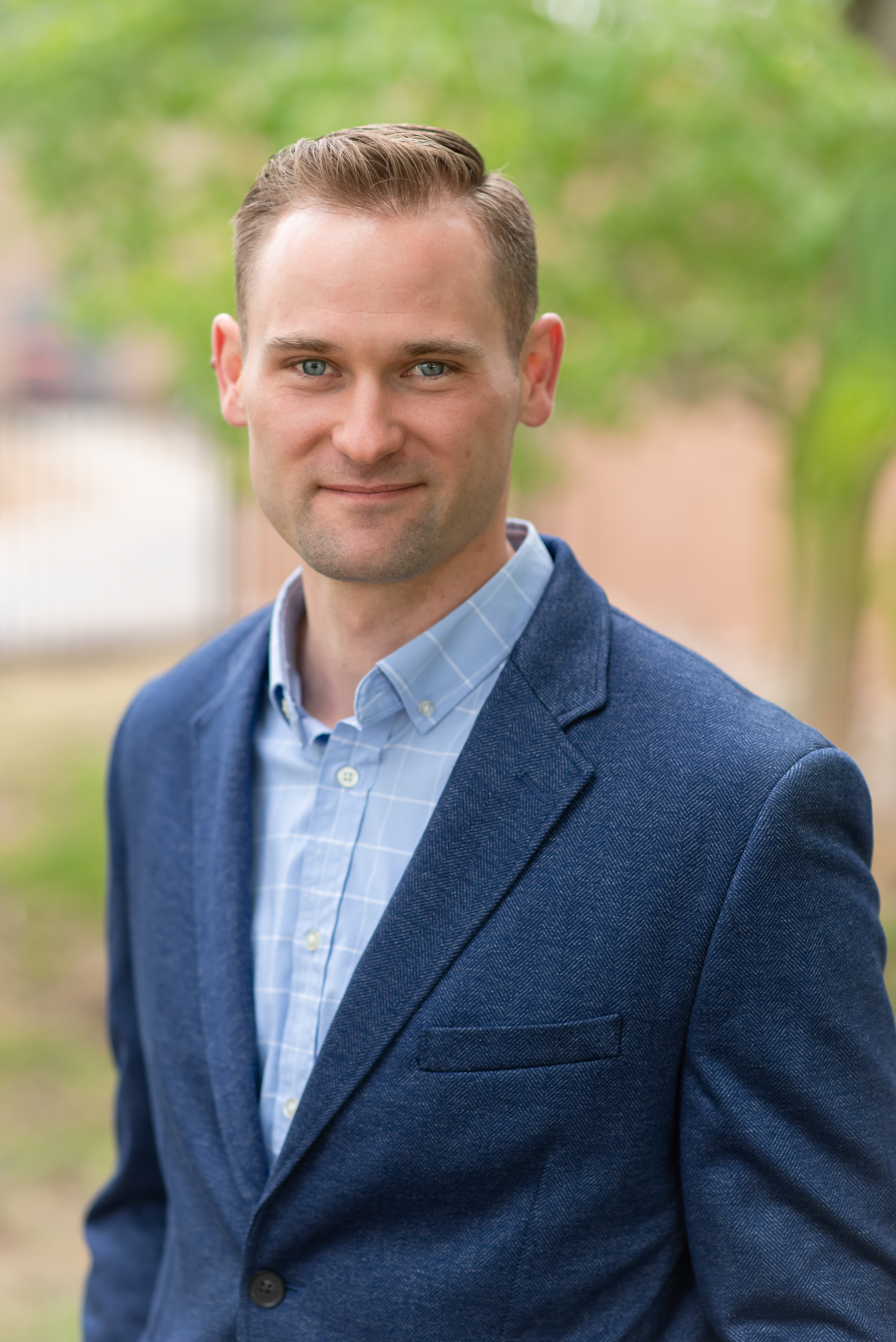 a man poses outside wearing a dress shirt and blazer