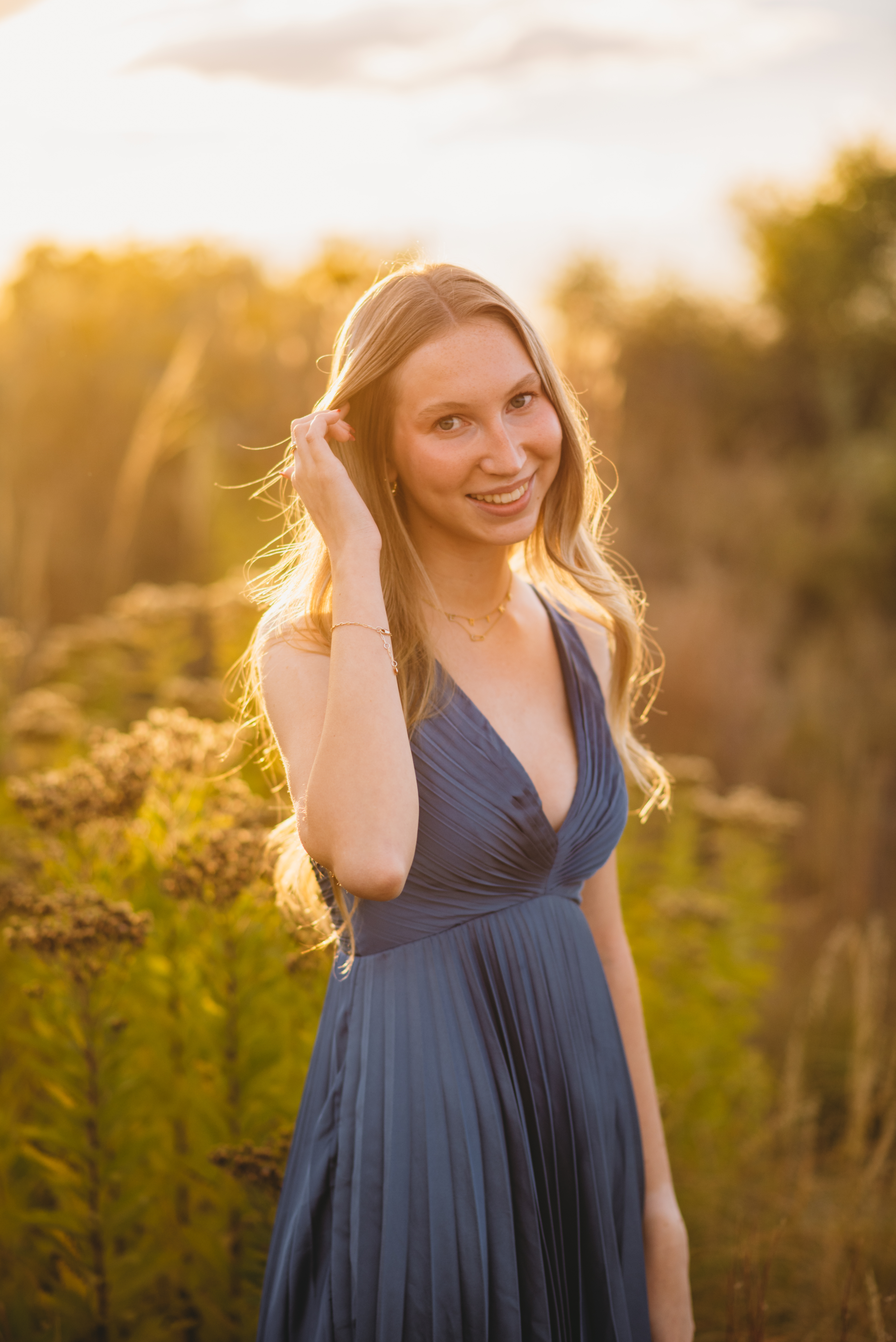 A senior girl poses for a photo in a blue dress.