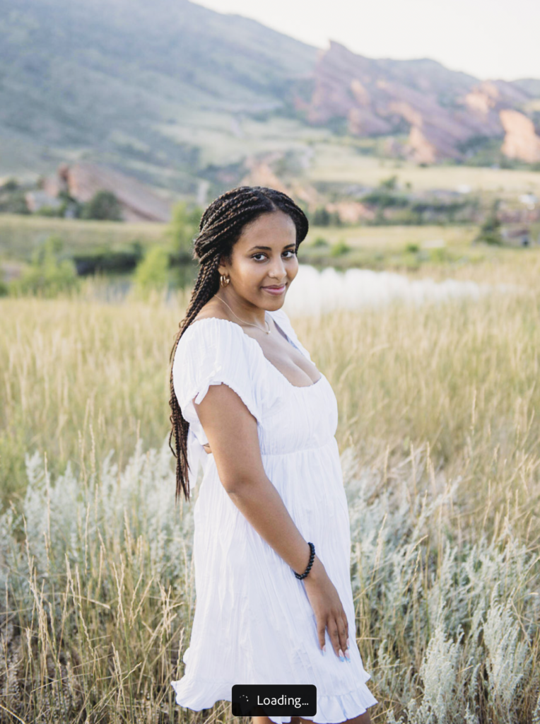 a girl in a white dress stands on a field in Denver Colorado.the joy of photographing seniors in denver 