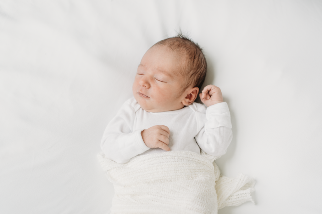 a baby is resting on a white blanket