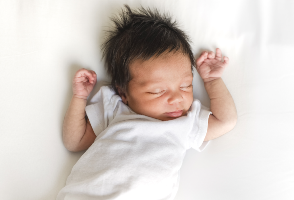 a newborn baby rests on a white backdrop