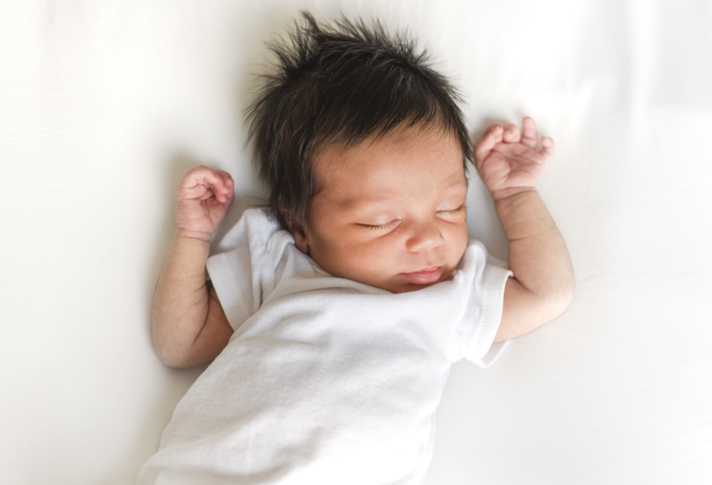 a newborn baby sleeps peacefully on a white blanket