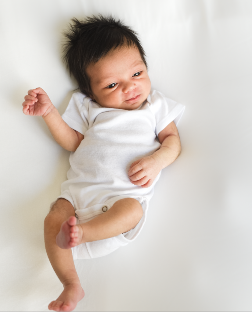 a newborn lays on a white backdrop 