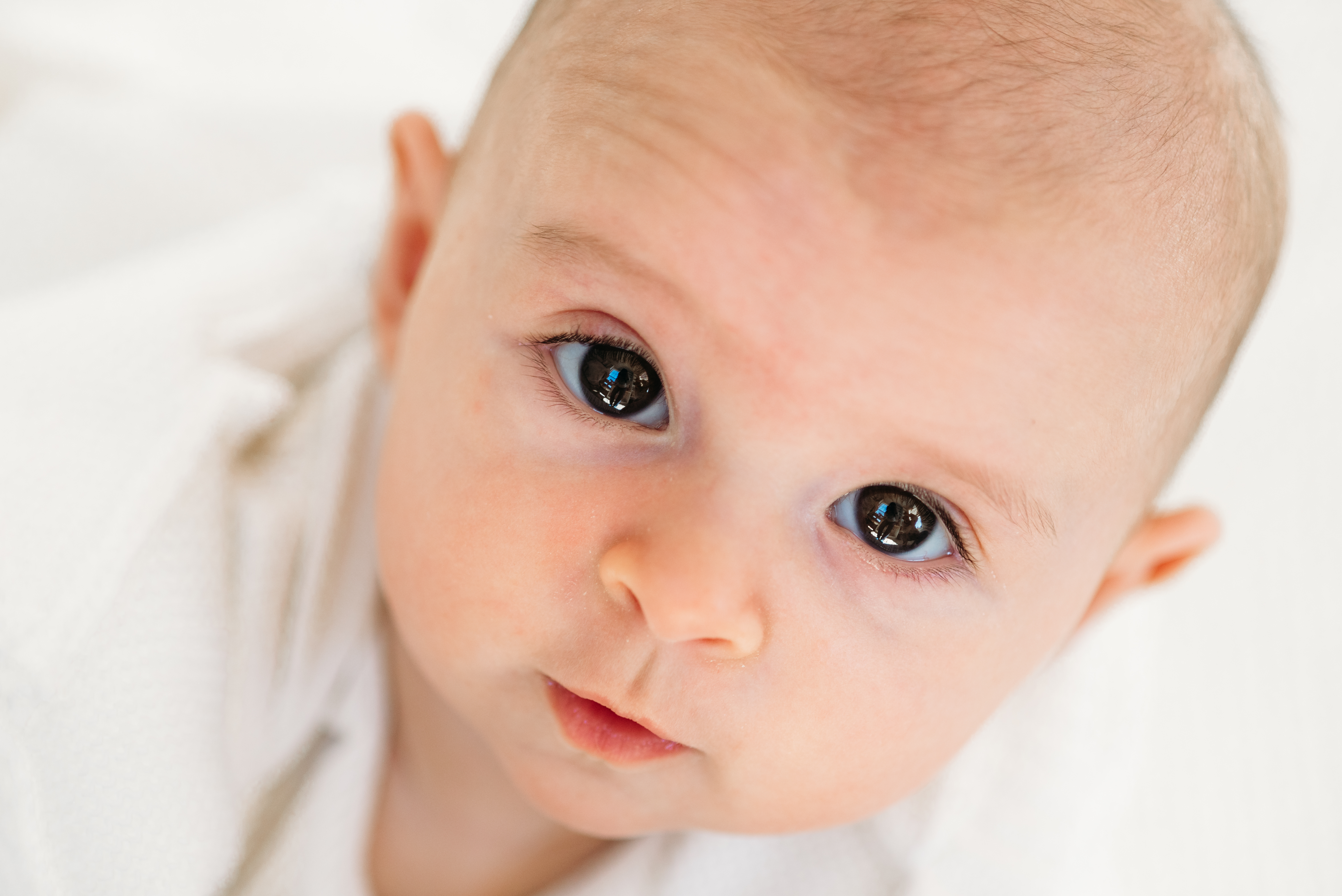 a close up shot of a 3 month old baby with big brown eyes