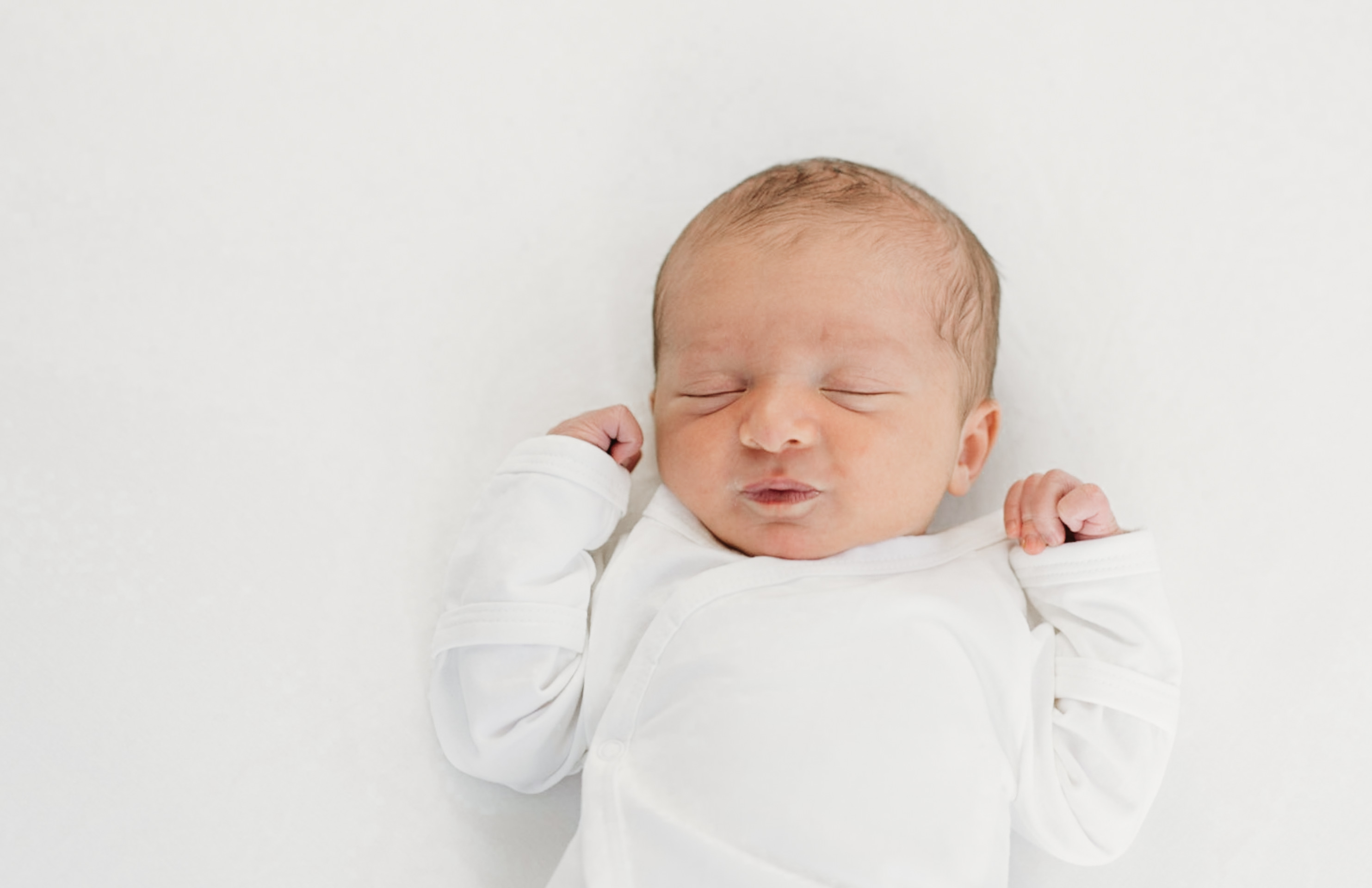 a newborn baby rests on a white blanket