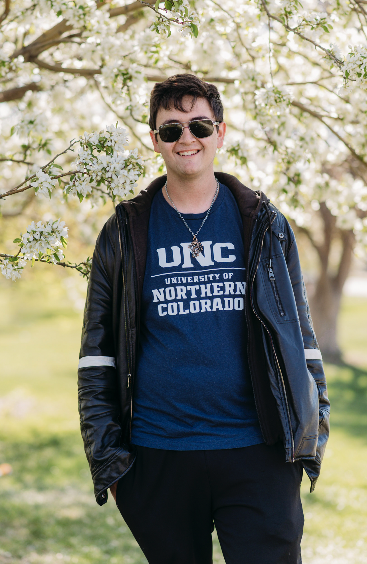 a boy in sunglasses poses for the camera wearing a college shirt