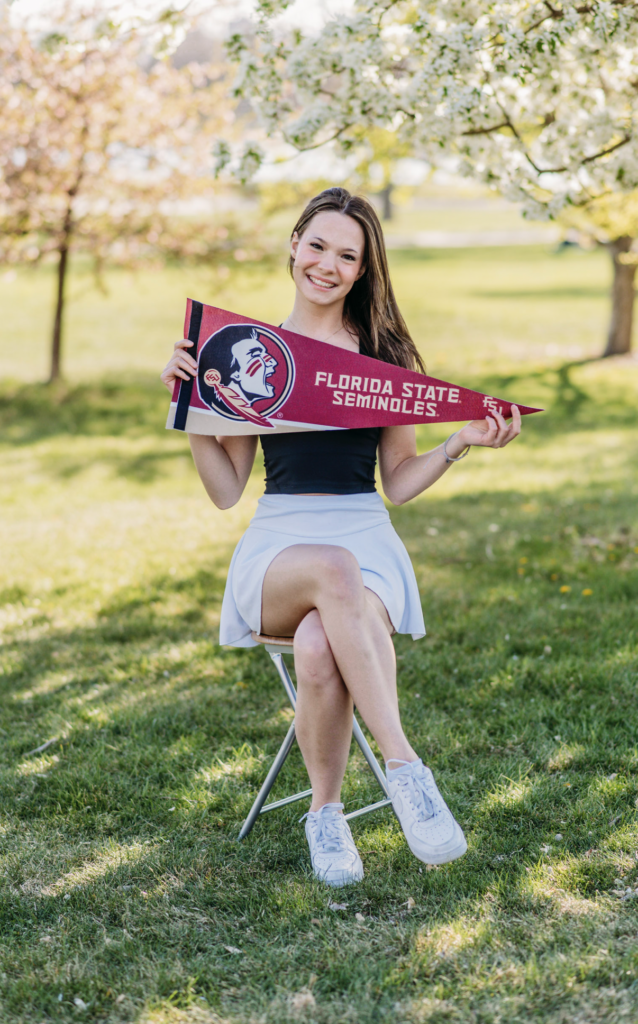 a senior girl sits holding a florida state flag